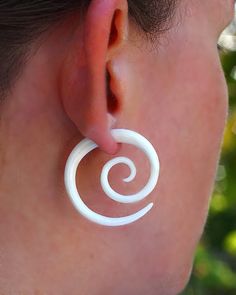 a close up of a person wearing large white hoops with spiral designs on them