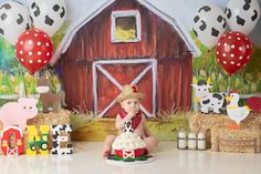 a baby sitting in front of a cake with farm animals on it