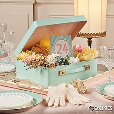 the table is set with an open box filled with flowers and lace gloves for decoration