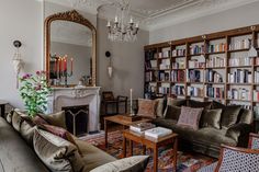 a living room filled with lots of furniture and bookshelves next to a fire place