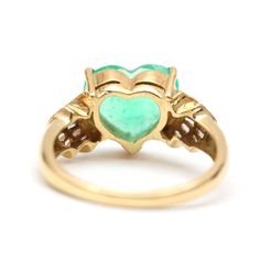 a gold ring with a heart shaped green stone