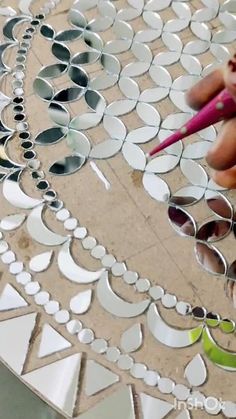 a person is holding a pencil and some mirrors on a table with holes in it