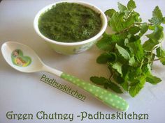 a bowl of green pest next to a spoon and sprig of parsley