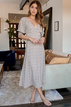 a woman standing in front of a couch wearing a dress with floral print on it