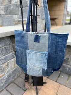 a handbag made out of jeans hanging on a brick wall