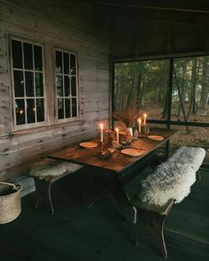 a wooden table with candles on it in front of a window and some sheepskin rugs