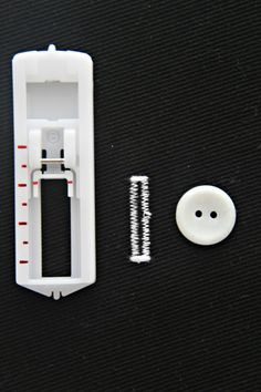 a white plastic case next to a button and screwdriver on a black surface