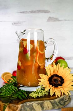 a pitcher of apple cider with sliced apples and orange slices