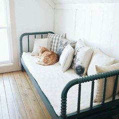 an orange cat laying on top of a bed in a room with wood flooring