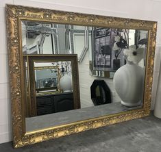 a large mirror sitting on top of a table next to a vase filled with flowers