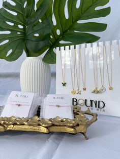 jewelry displayed on display in front of a white vase with green leaves and card holders