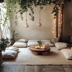 a living room filled with lots of plants and pillows on top of a wooden table