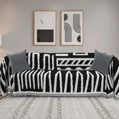 a black and white couch sitting in a living room next to two pictures on the wall