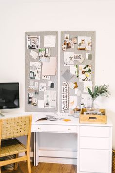 a white desk topped with a computer monitor next to a cork board covered in pictures