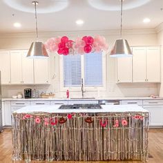 a kitchen filled with white cabinets and pink balloons