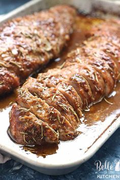 meat covered in gravy sitting on top of a baking pan with sauce and seasoning