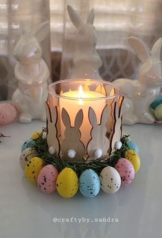 a candle that is sitting on a table with some easter eggs in front of it