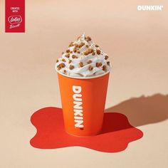 an orange dunkin'donuts cup with whipped cream and sprinkles