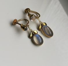 "Please check my own website at www.elegantium.co.uk for my best prices :-) A wonderful extremely rare pair of antique Arts and Crafts earrings by Liberty & Co of London, c1910. They have been crafted in 9ct gold (stamped on the screw back) and show four flashy Ceylon blue moonstones. I adore these stones and the way they flash from clear to the vibrant blue you can see in the images. A similar pair, also with a foliate design,  was sold historically at the fabulous Tadema Gallery in London. I h Vintage Moonstone Jewelry Collectible, Antique Wedding Cabochon Earrings, Vintage Gold Moonstone Jewelry, Antique Clip-on Earrings For Anniversary, Victorian Gold Jewelry With Moonstone, Victorian Gold Moonstone Jewelry, Victorian Moonstone Gold Jewelry, Antique Yellow Gold Clip-on Earrings, Sandra Brown