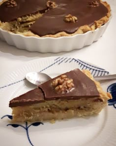 a piece of pie sitting on top of a white plate next to a bowl filled with nuts