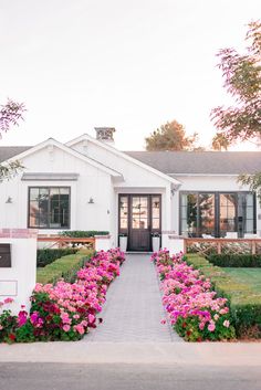 a white house with pink flowers in the front yard