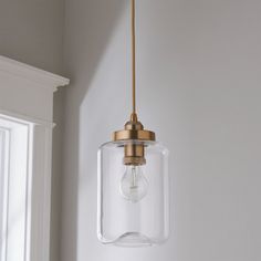 a clear glass light hanging from a ceiling in a room with white walls and windows