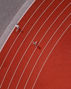 two men running on a red track with white lines