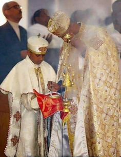 two men dressed in white and gold standing next to each other