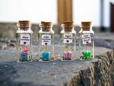 three glass bottles with tiny gifts in them sitting on a stone ledge next to a building