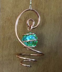 a wire wrapped pendant with a green stone in the center and spiral design around it