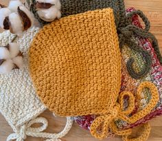 several crocheted bags are sitting on the floor next to cotton balls and yarn