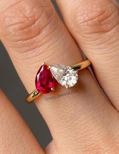 a woman's engagement ring with two pear shaped ruby and diamond stones on it