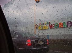 rain drops on the windshield of a car in front of a children's world sign