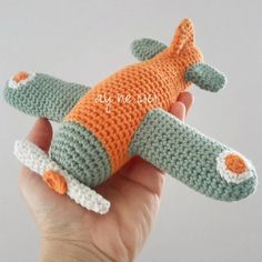 a hand holding an orange and green crocheted toy with a small alligator on it