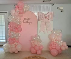 a baby shower is set up with balloons and bows on the wall, along with an arch