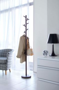 a coat rack with clothes hanging on it and a lamp in the corner next to it