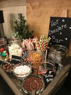 a table topped with lots of candy and candies next to a sign that says hot chocolate bar