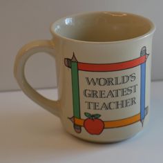 a coffee cup with the words world's greatest teacher on it and an apple