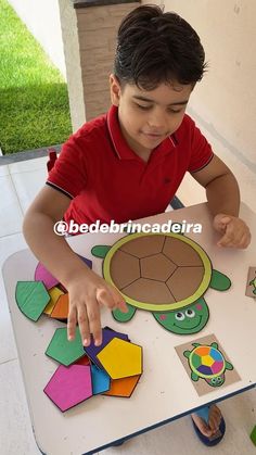 a little boy that is sitting at a table with some cut out animals on it