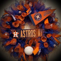 an orange and blue wreath with baseballs on it that says astros in the center