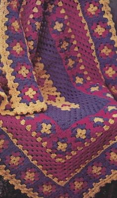 a purple and yellow crocheted blanket sitting on top of a chair