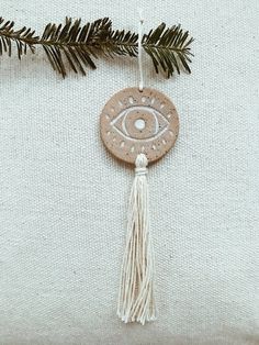 an ornament hanging from a tree branch with a small evil eye on it