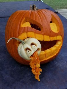 a carved pumpkin with an evil face on it's side and a bone in its mouth