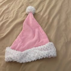 a pink and white santa hat laying on top of a bed