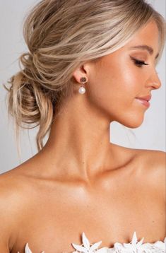 a woman with blonde hair wearing a white off the shoulder top and earrings on her head