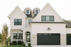 a white house with black garage doors and windows