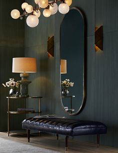 a room with a bench, mirror and lamps