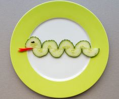 a plate with cucumber slices cut in the shape of letters on it and an orange toothpick sticking out of the middle