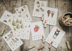 several matching cards with animals and numbers on them next to a basket of clothes pins