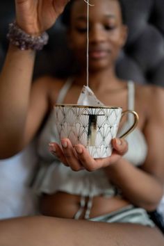 a woman is holding a tea cup in her hand